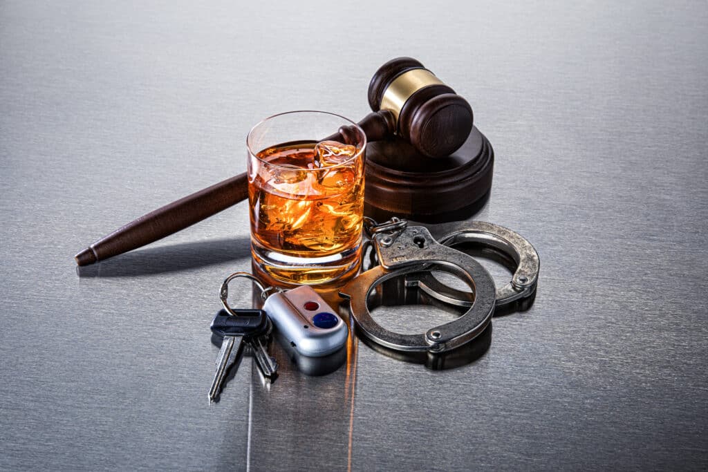 Don"u2019t drink and drive A judge's gavel behind a glass of alcohol and handcuffs