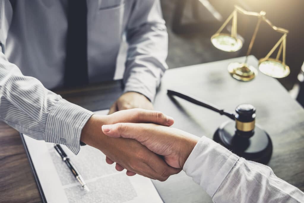 Handshake after good cooperation, Businessman handshake male lawyer after discussing good deal of Trading contract and new projects for the company of real estate, Meeting and greeting concept Two people shaking hands over a desk with a book and a judge's gavel